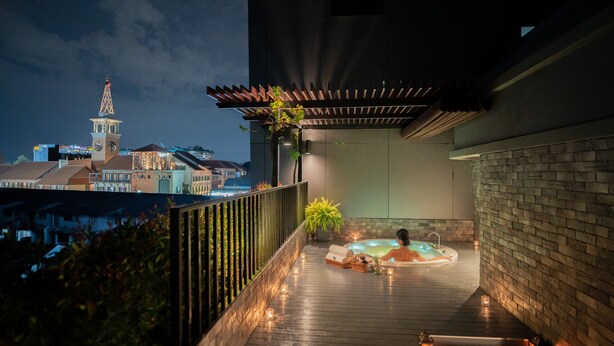 En tagterrasse med jacuzzi, træterrasse og udsigt over bybilledet, inklusive et tårn med et ur.