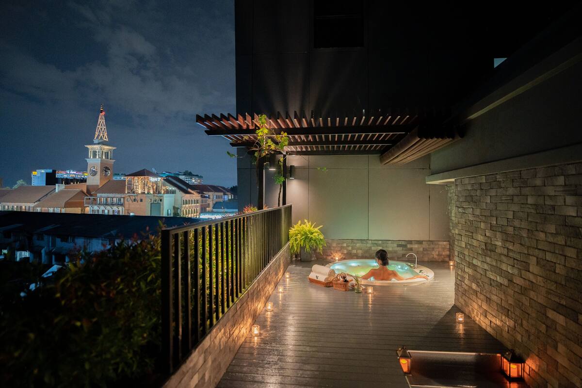 A rooftop terrace with a hot tub, wooden deck, and a view of a cityscape including a clock tower.