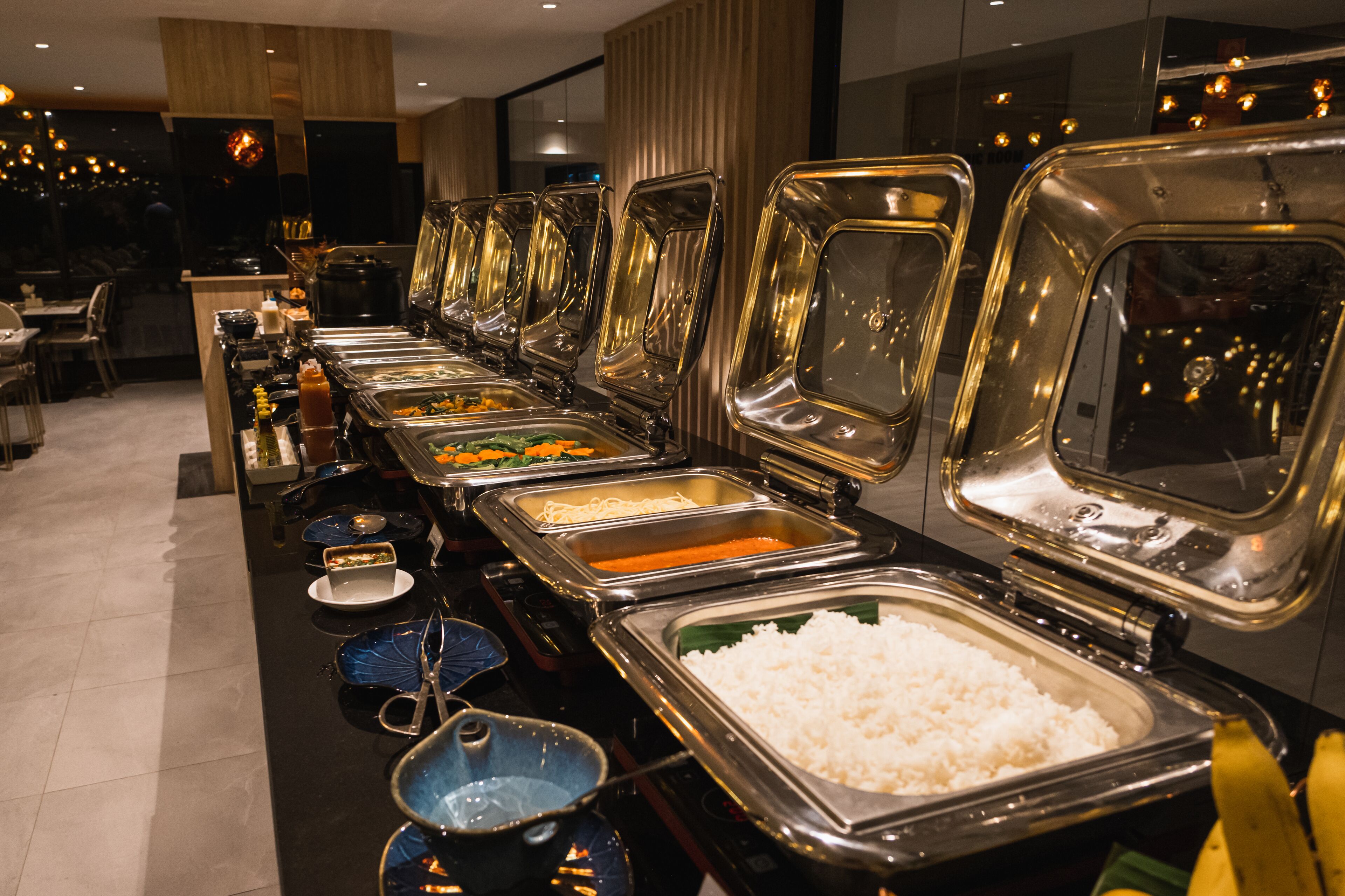 A buffet setup with various food items and utensils.