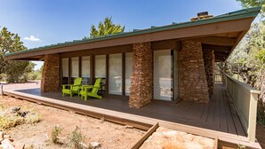Ein modernes Haus mit Steinaußenwand, großen Fenstern und einer Holzterrasse.