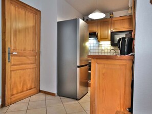 Eine Küche mit Holzschränken, einem Edelstahlkühlschrank, einer Mikrowelle und einem Wasserkocher.