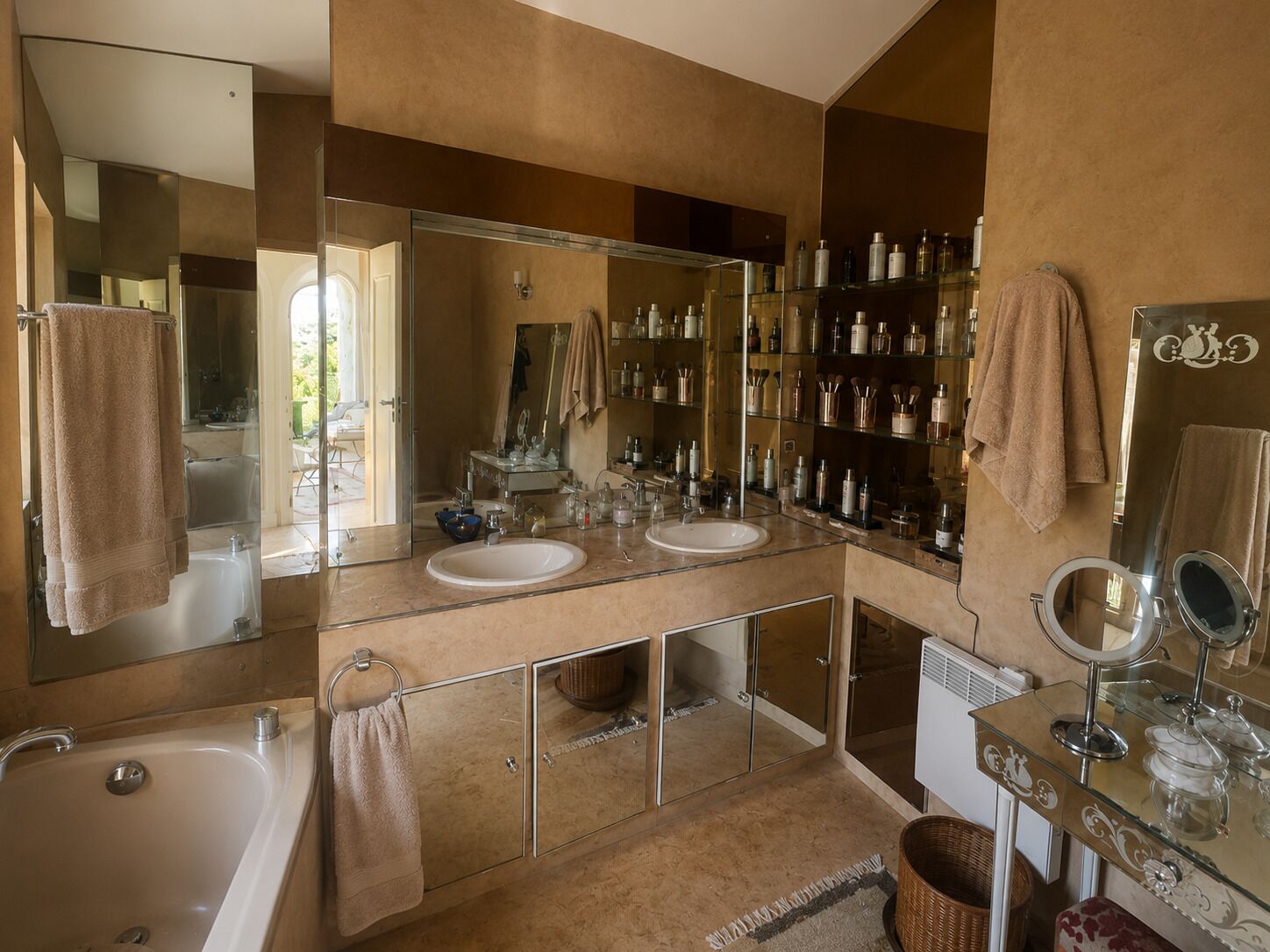 Une salle de bain avec deux lavabos, un grand miroir et un meuble en verre contenant des articles de toilette.