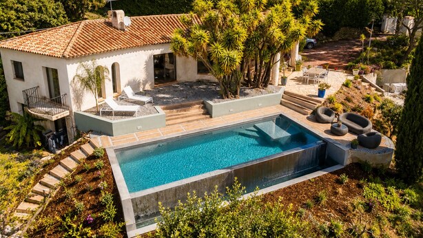 En modern villa med pool, utomhusmöbler och en trädgård.