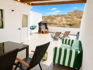 A balcony with wicker furniture, a striped sofa, and a hanging chair. - Large quiet terrace. Only 150 m to the sea. (La Caleta)