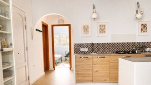 Una cocina con armarios de madera, encimera blanca y salpicadero azulejado.