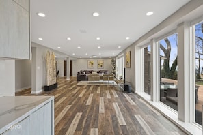 Un salon spacieux avec un grand canapé, une table basse et une cheminée. De grandes fenêtres offrent une vue sur l’extérieur.