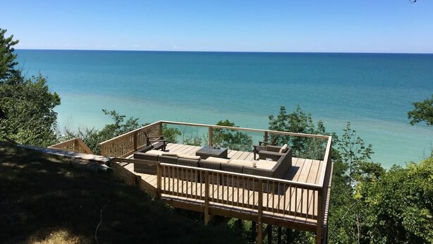 Une terrasse en bois avec des sièges extérieurs, donnant sur une mer d’un bleu limpide.