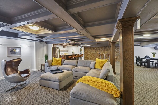 A modern living room with a sectional sofa, a unique chair, and a dining area with chairs and a table.