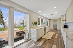 Une cuisine moderne dotée d’une grande fenêtre, offrant une vue sur l’extérieur, et d’un plancher en bois.