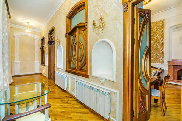 A spacious hallway with a glass railing, wooden doors, and a fireplace.
