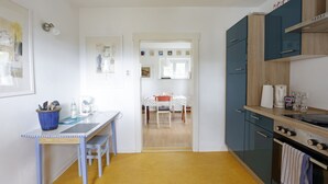 Una cocina con una mesa de comedor, sillas, una cafetera y armarios.