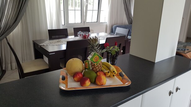 A fruit tray on a kitchen counter with a dining table and chairs in the background. - Silver villa Raches, Green, Kite Surfers Spot (Raches, Fthiotida)