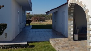 A building with a paved courtyard, a stone archway, and a grassy area. - Silver villa Raches, Green, Kite Surfers Spot (Raches, Fthiotida)