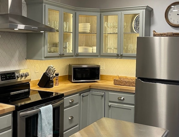 Enjoy cooking in this well-equipped kitchen with a stainless steel refrigerator, microwave, oven, and stovetop.