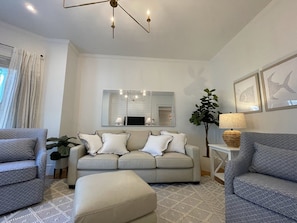 Relax in this stylish living room with a beige sofa, two armchairs, and a white ottoman.