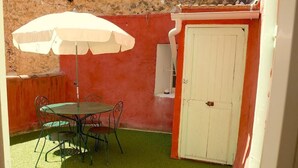 A patio with a table and chairs, a white umbrella, and a door. - Provencal loft with terrace in the heart of the village (salernes)