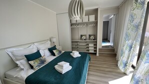 Un lit bien fait, avec du linge de lit blanc et une couvre-lit turquoise, une lampe de chevet et une armoire avec un miroir et des étagères.