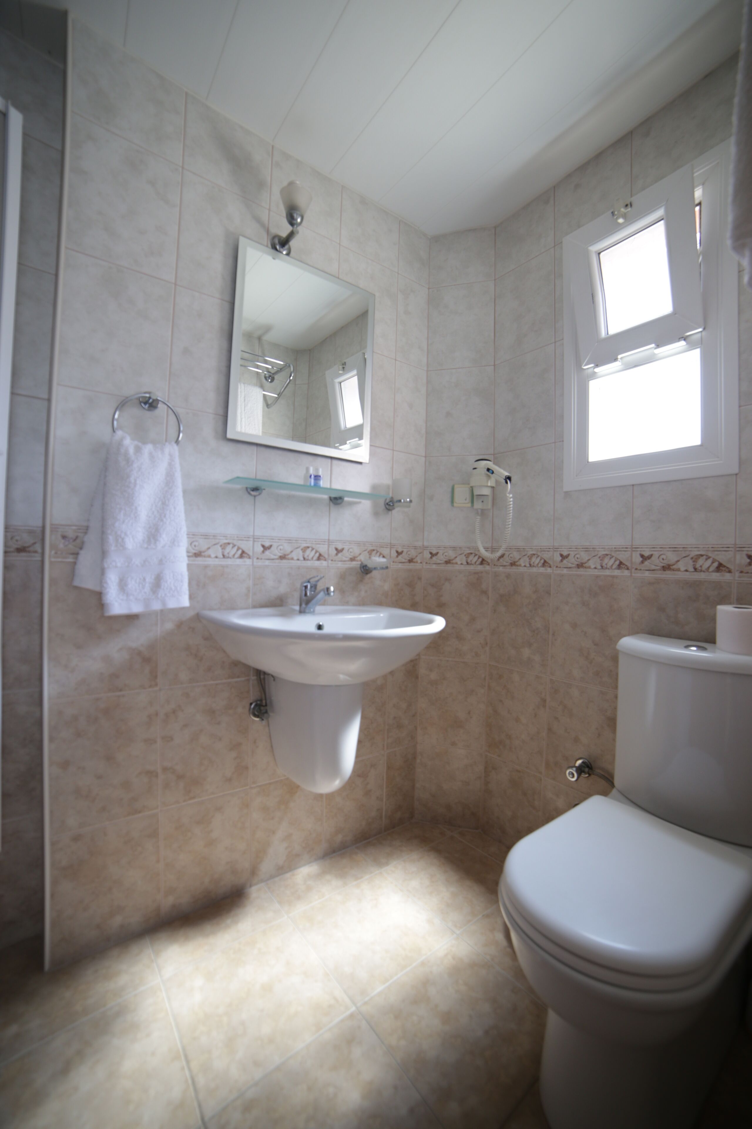 Ein Badezimmer mit Waschbecken, Spiegel, Toilette und einem Fenster.