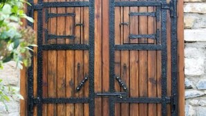 A wooden double door with black metal hinges and a stone wall background. - Nazar Hotel (Selçuk)