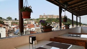 A balcony with a view of a historic castle, wooden furniture, and hanging planters. - Nazar Hotel (Selçuk)