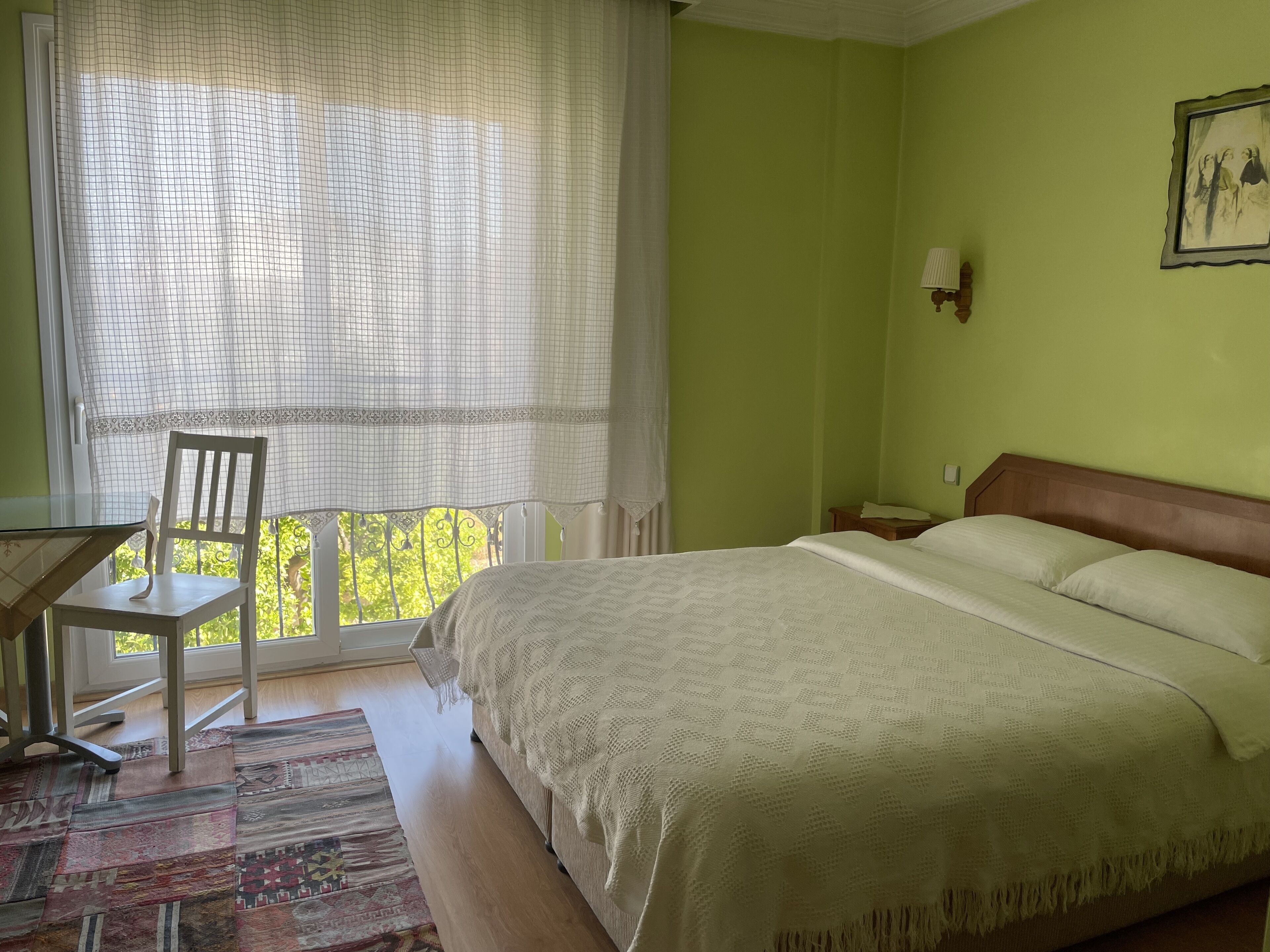 A bedroom with a bed, a chair, a desk, and a window with curtains.