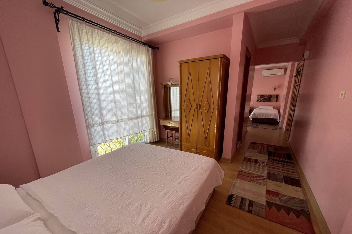 A bedroom with a bed, a wardrobe, a desk, and a small bathroom.