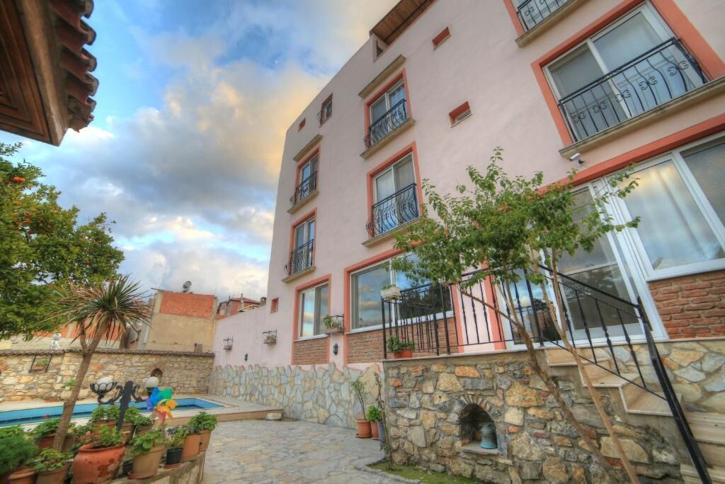 Un immeuble à plusieurs étages doté de balcons, d’un mur en pierre et d’une piscine.