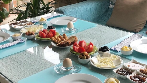 A breakfast table with various dishes, a stone wall, and a view of greenery outside. - Nazar Hotel (Selçuk)