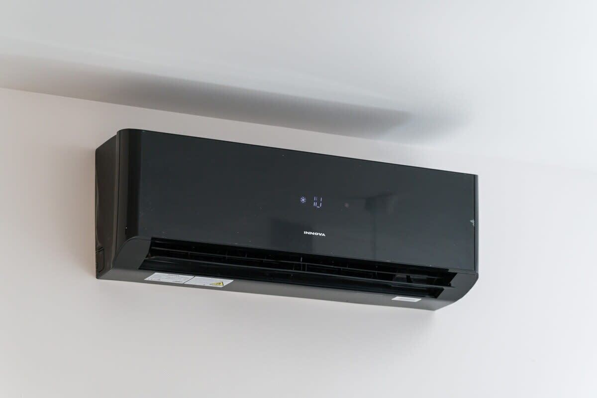 A black air conditioning unit mounted on a white wall.