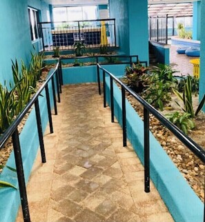 Stroll through the corridor to the pool area, surrounded by lush greenery and a tranquil atmosphere.