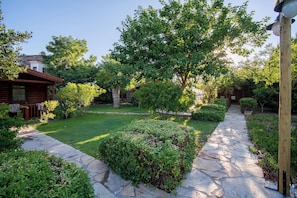 A stone pathway leading through a well-maintained garden with various shrubs and trees.