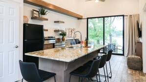 Una cocina moderna con una isla grande, refrigerador negro y un comedor con sillas.