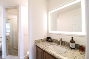 A bathroom with a glass shower enclosure, a sink with a marble countertop, and a large mirror. - Luxe Lakeside•Lake Views•Couples•Families•Kings (Grove)