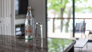 A bottle of Acqua Panna on a marble countertop with a clear glass beside it. - Lakeside Modern Luxury Cabin with Lake View (Grove)