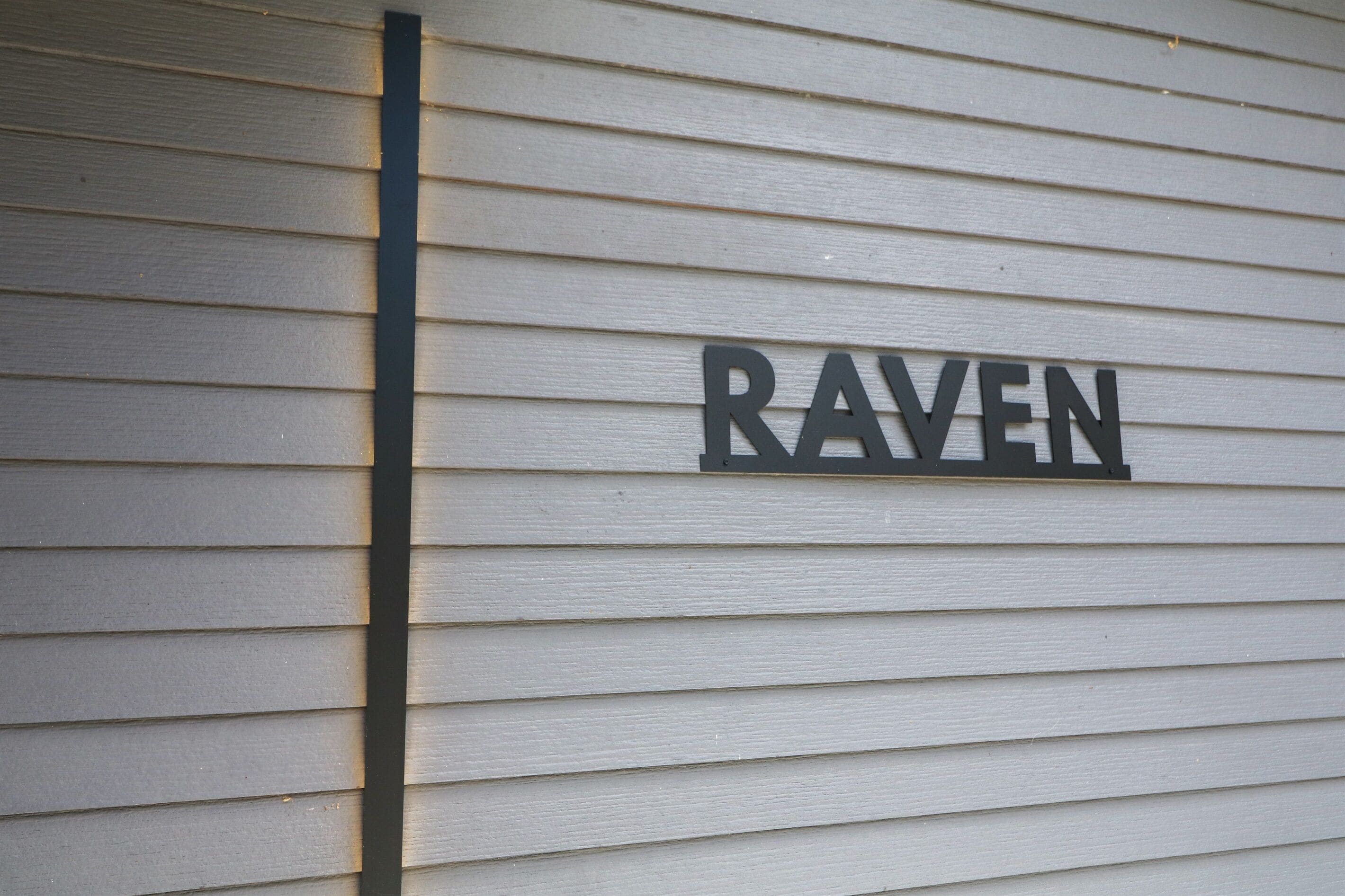 Ein Gebäude, auf dessen heller Außenwand der Schriftzug „RAVEN“ zu sehen ist.