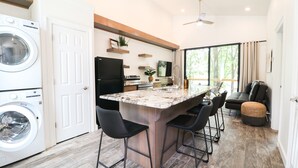 A modern kitchen with a central island, built-in appliances, and a dining area with bar stools. - Lakeside Modern Luxury Cabin with Lake View (Grove)
