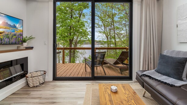 Una sala de estar moderna con un ventanal corredero que da a una terraza, un sofá, una mesa de centro y una chimenea.