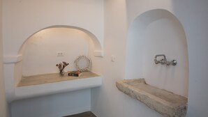 Un bagno con pareti bianche, due lavabi in pietra e un soffitto con travi in legno.