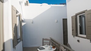 Una stanza piccola con pareti bianche, un tavolo, sedie, una finestra e una porta.