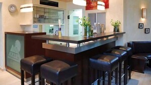 A modern kitchen with a central island, bar stools, pendant lighting, and a clock on the wall. - Adam Hotel - Giesen (Giesen)