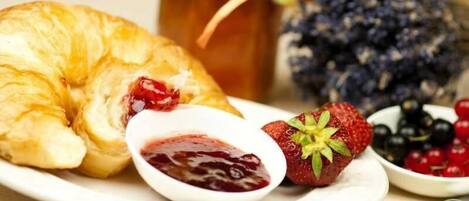 A plate with a croissant, strawberry, and berry compote.