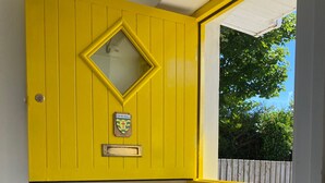 A room with a yellow door, a white radiator, and a black and white checkered floor. - The Yellow Door Cottage (Moville)