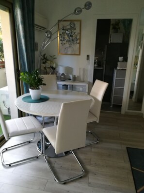 A dining area with a round table, white chairs, a potted plant, and a modern floor lamp. - Cosy, green apartment (Cannes)