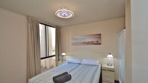 Une chambre d’hôtel comprenant un lit, deux lampes de chevet, une table de nuit, une fenêtre avec des rideaux et un tableau accroché au mur.