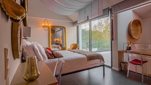 A modern bedroom with a large bed, a desk, and a chair. There is a window with a view of trees and a balcony. - Villa Cerrado das Fontainhas (Sintra)