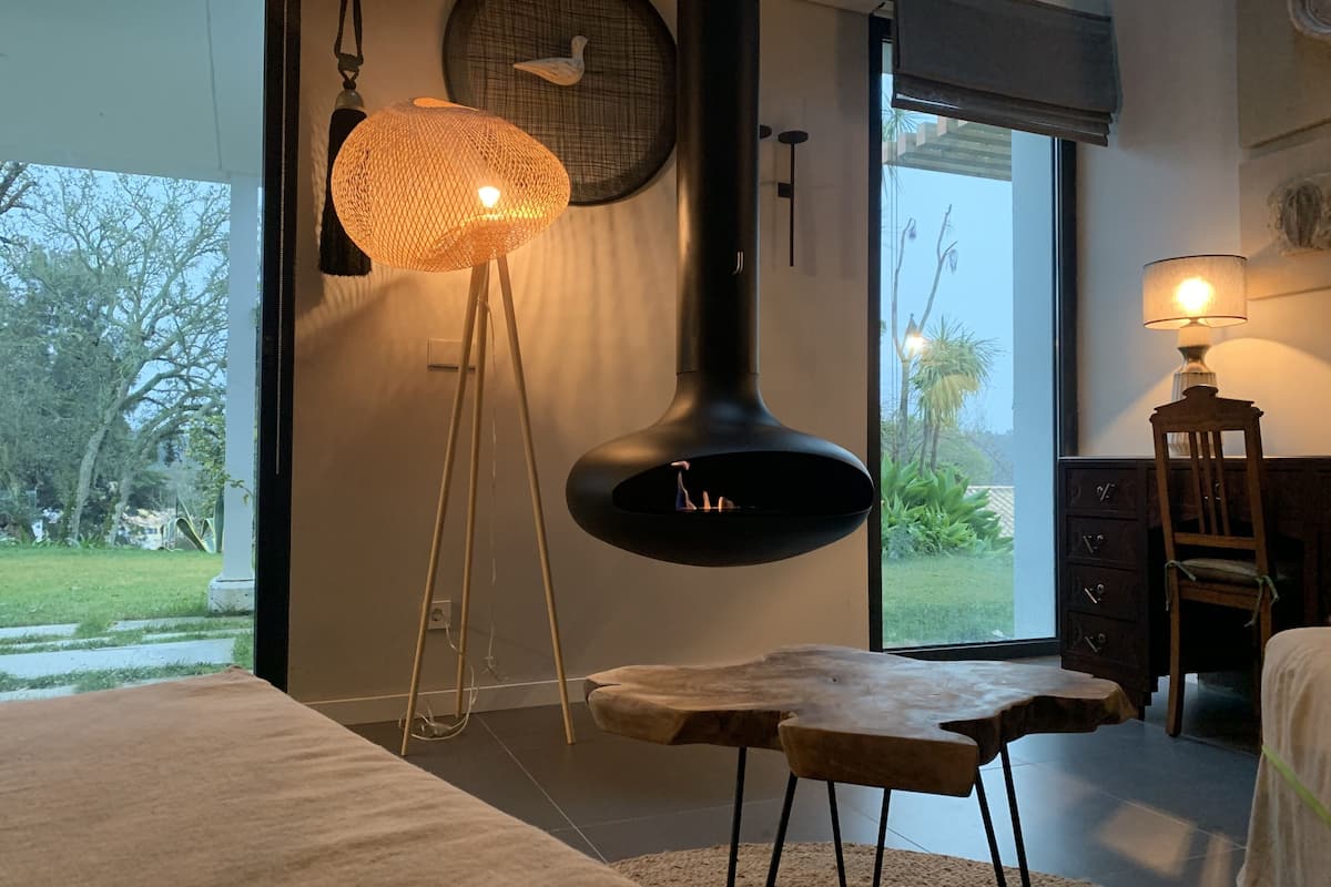 A modern room with a large window, a standing lamp, a wooden table, and a chair.