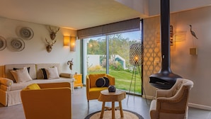 A modern living room with a sofa, armchairs, a round wooden table, and a fireplace. - Villa Cerrado das Fontainhas (Sintra)