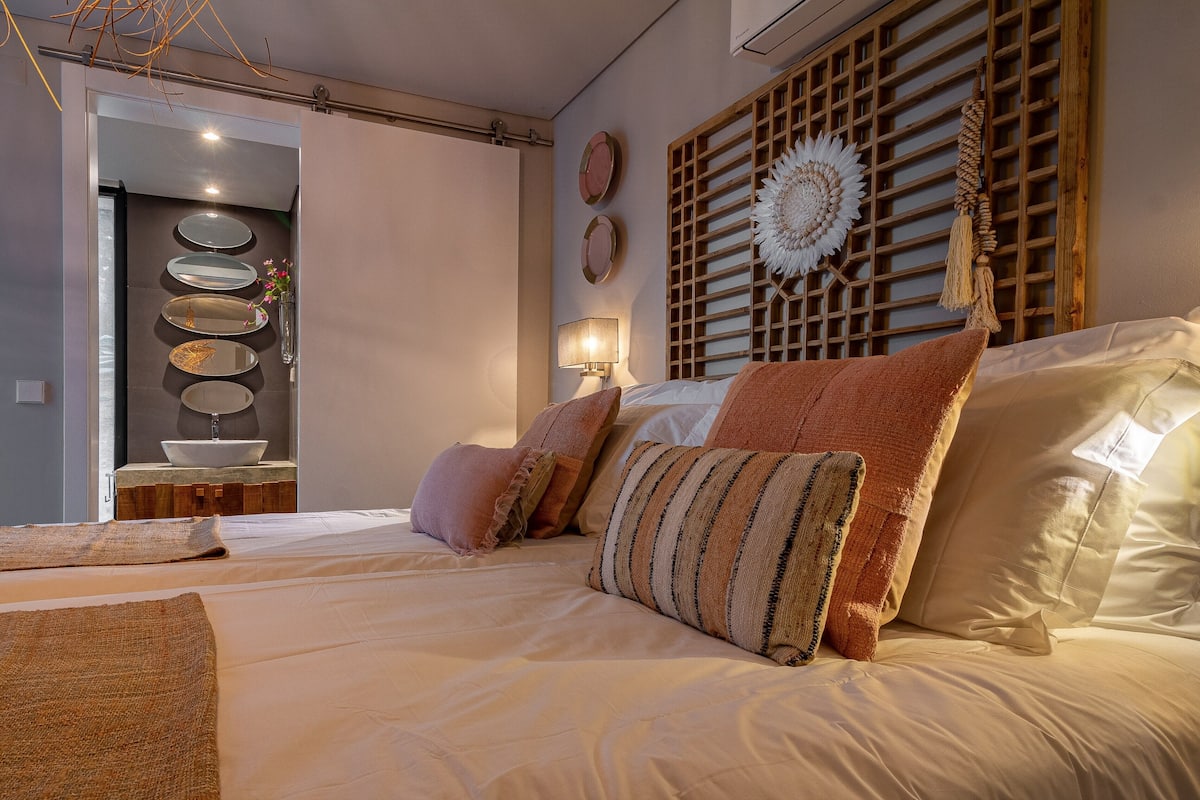 A bedroom with a large bed, a wooden headboard, and a bedside table with a lamp.