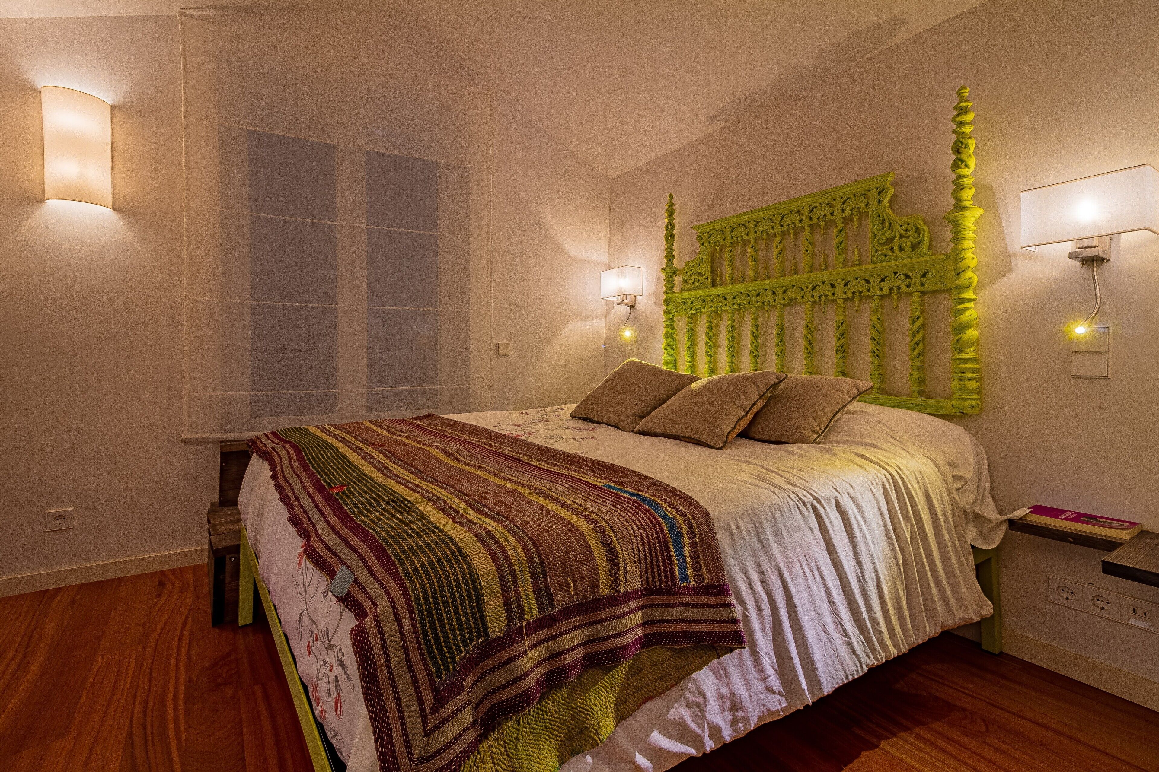 A bedroom with a bed, a window, and a green headboard.