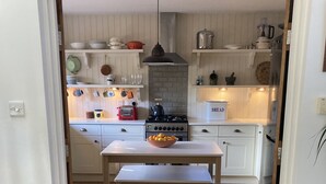 Een keuken met witte kastjes, een houten vloer en een tafel met een fruitschaal.